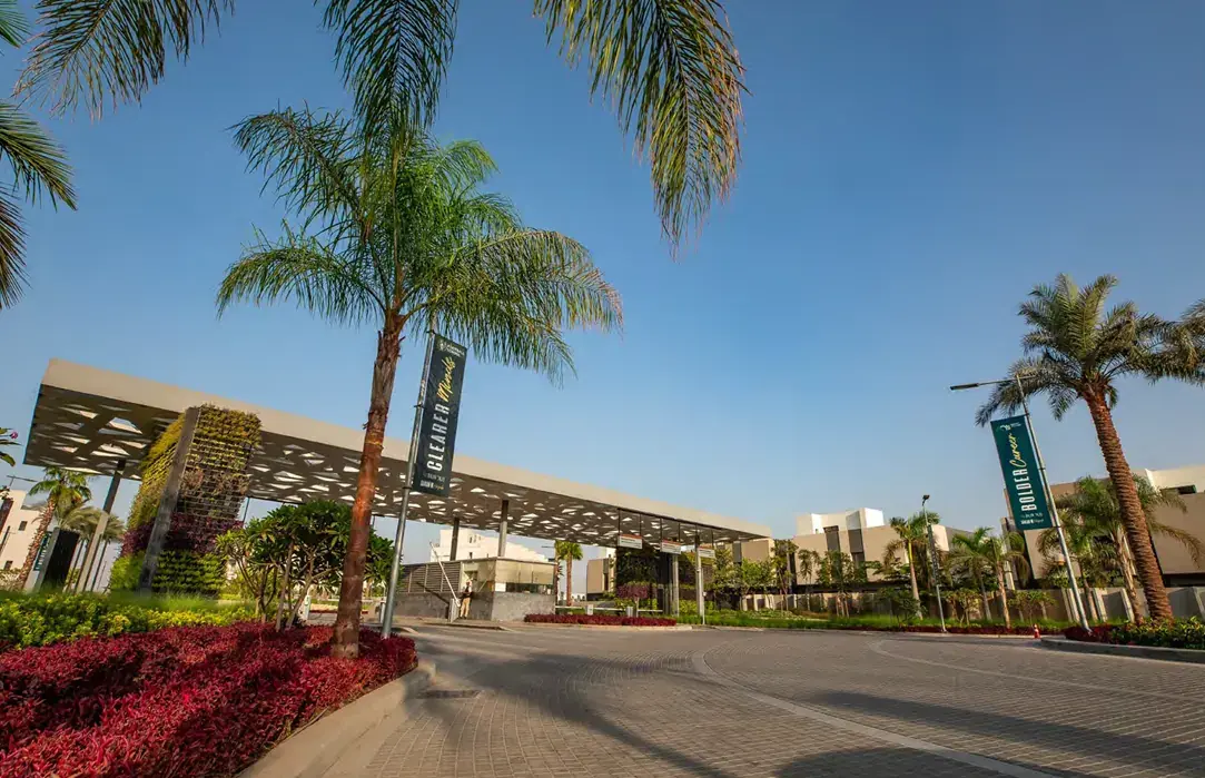 Al Burouj main gate with palm trees and flower beds